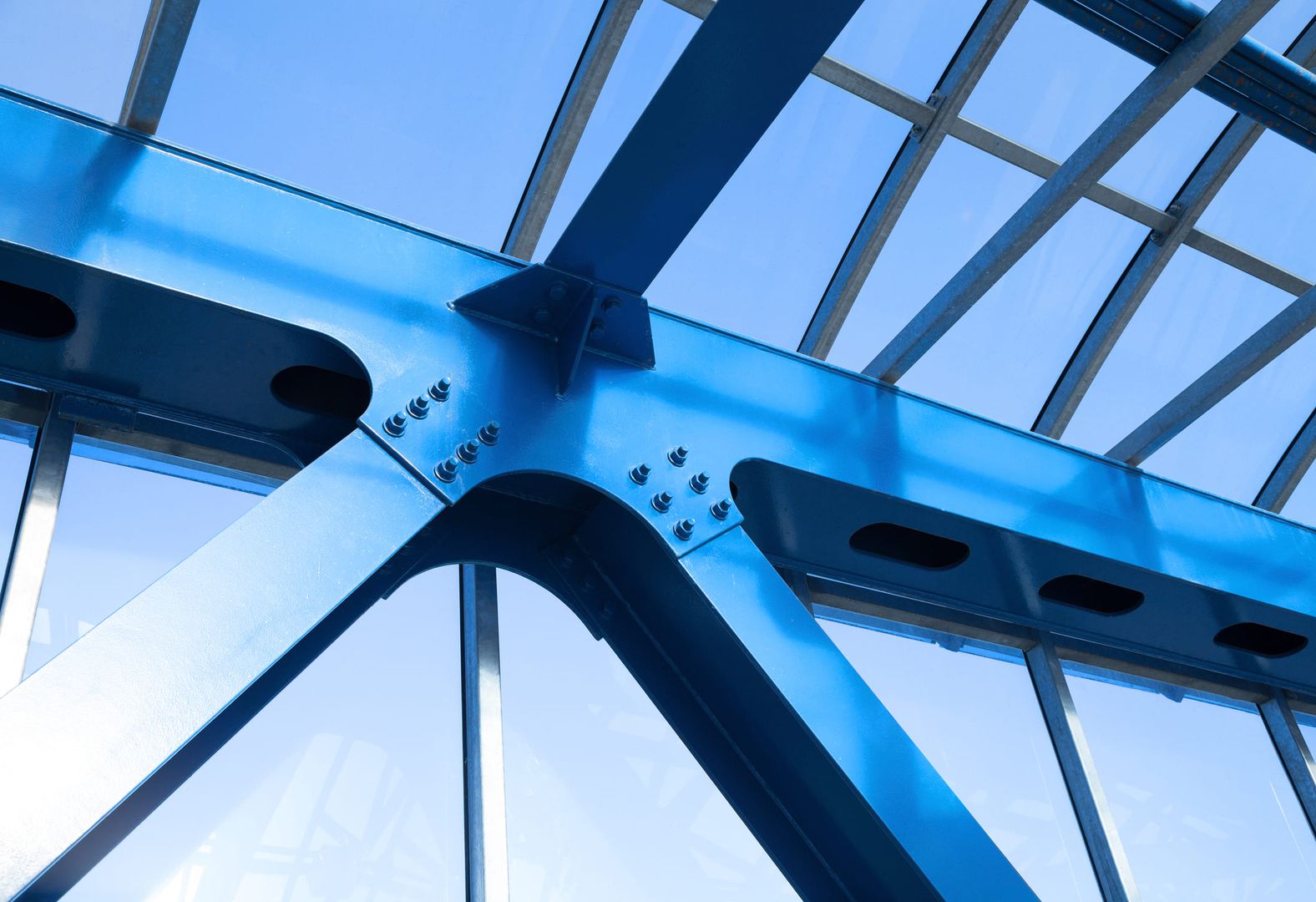Blau lackierte Stahlträger mit Schraubverbindungen einer Stahlkonstruktion unter Glasdach